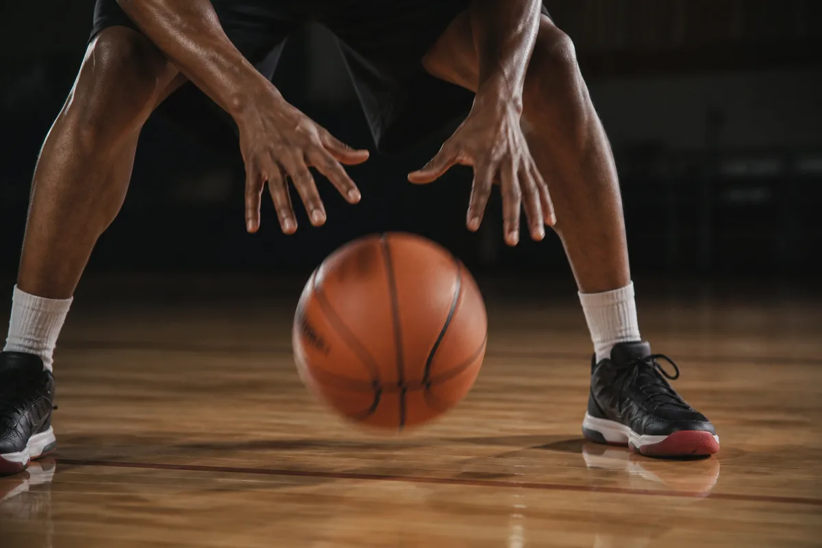 Mains d un basketteur poussant le ballon vers le sol en dribble bas