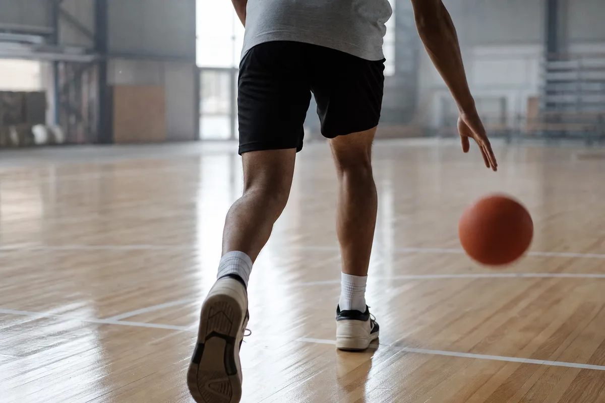 Un basketteur remonte le ballon en dribble sur un parquet de gymnase