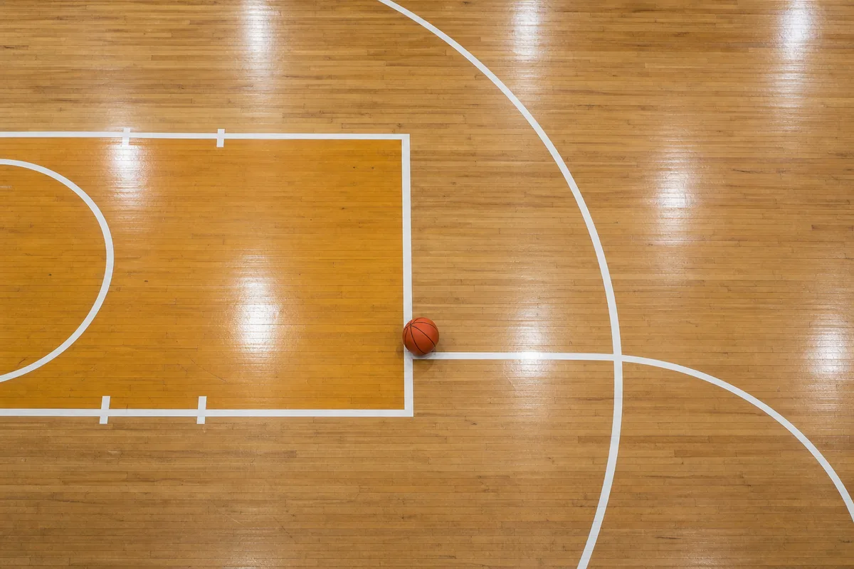 Lignes de la raquette et ballon posé sur le parquet d&rsquo;un gymnase