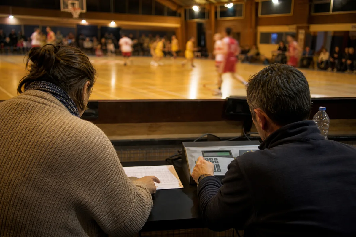 Deux bénévoles concentrés derrière le pupitre de chronométrage pendant un match